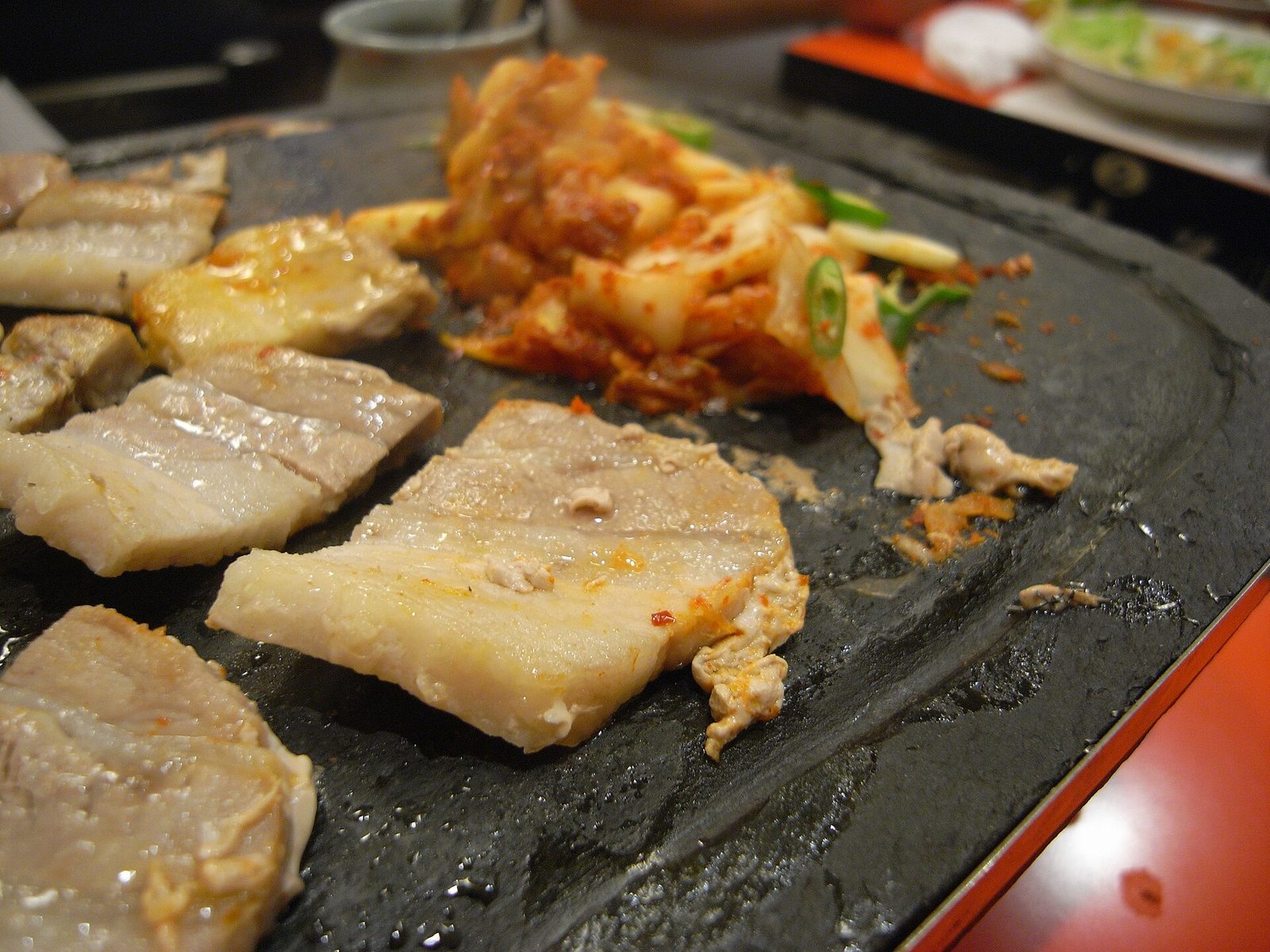 Grilled meat cooking at a Korean BBQ table with lettuce and side dishes