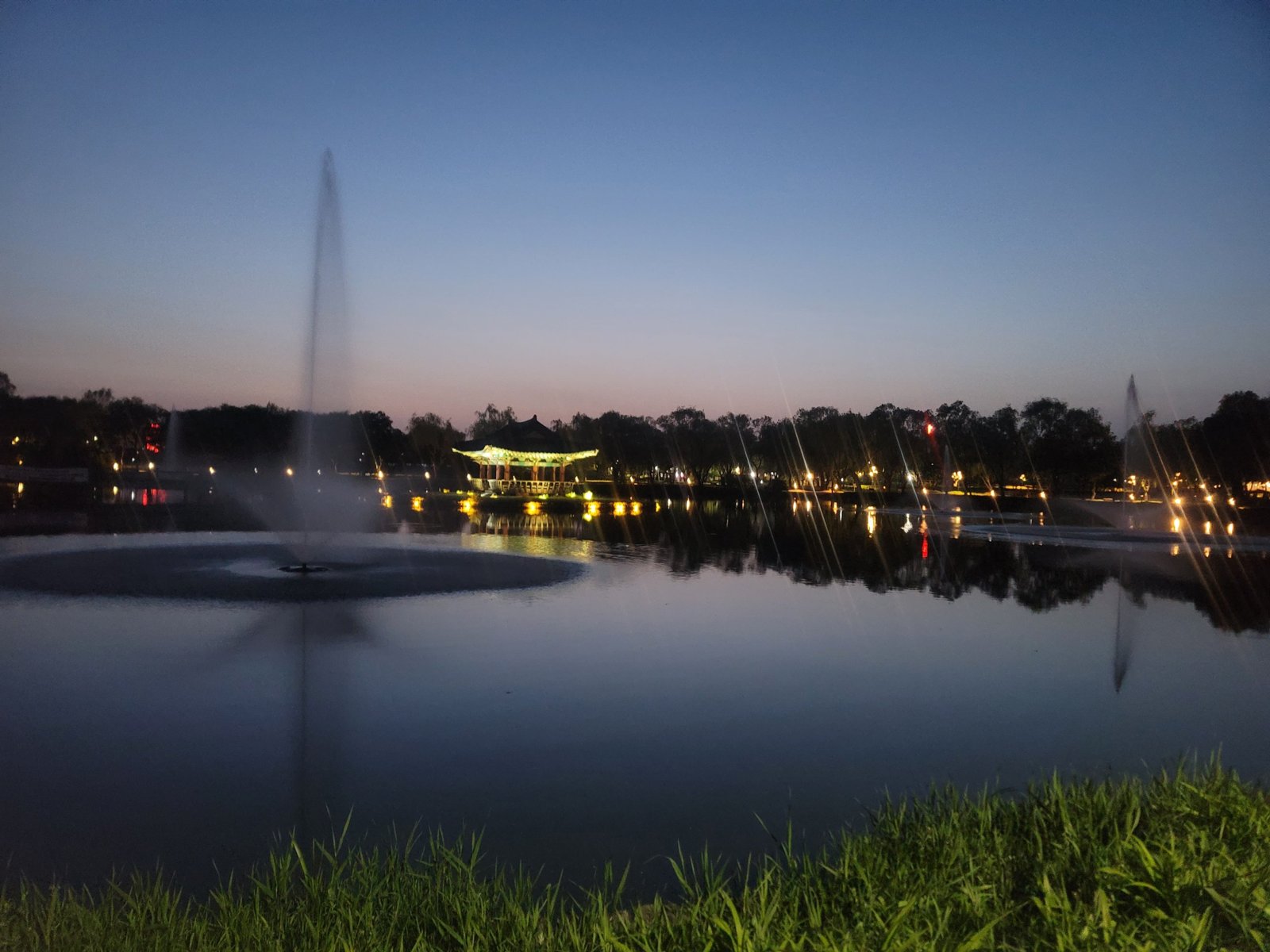 Fountains and the lit pavilion on Gungnamji pond just after sunset