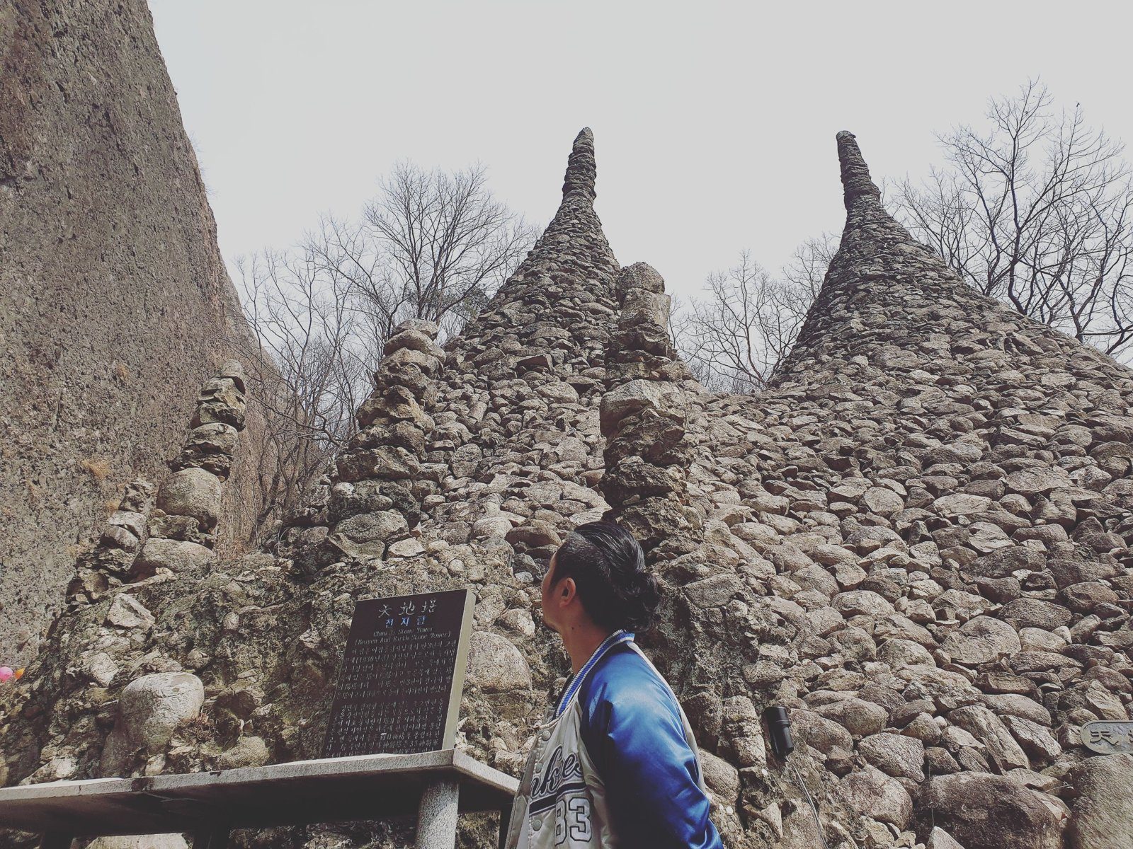 The twin Cheonji stone towers at Tapsa, with a visitor looking up at them