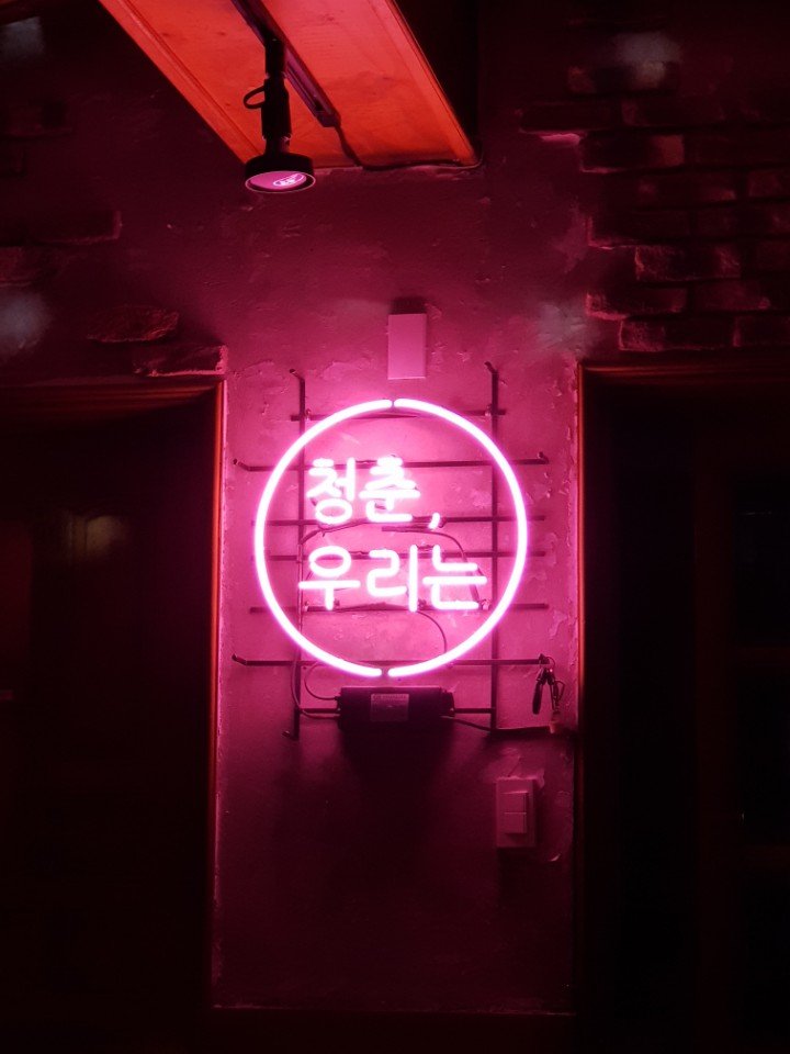 A pink neon sign written in Hangul, the kind of Korean text a translation app can read